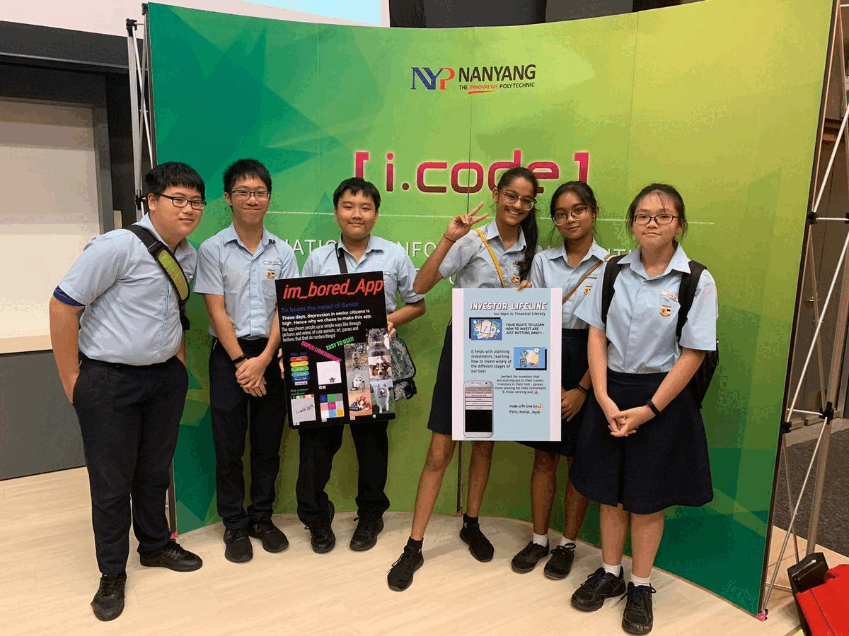 Six students in school uniforms pose holding two project posters in front of a green Nanyang i.code1 backdrop.